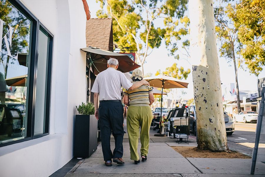 elderly couple walking down sidewalk