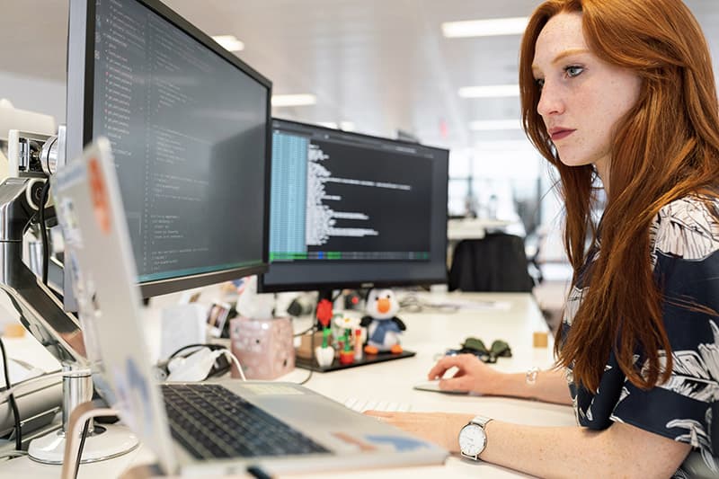 red haired woman working in front of a computer