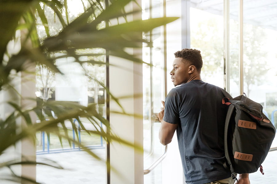 student with backpack walking out of door